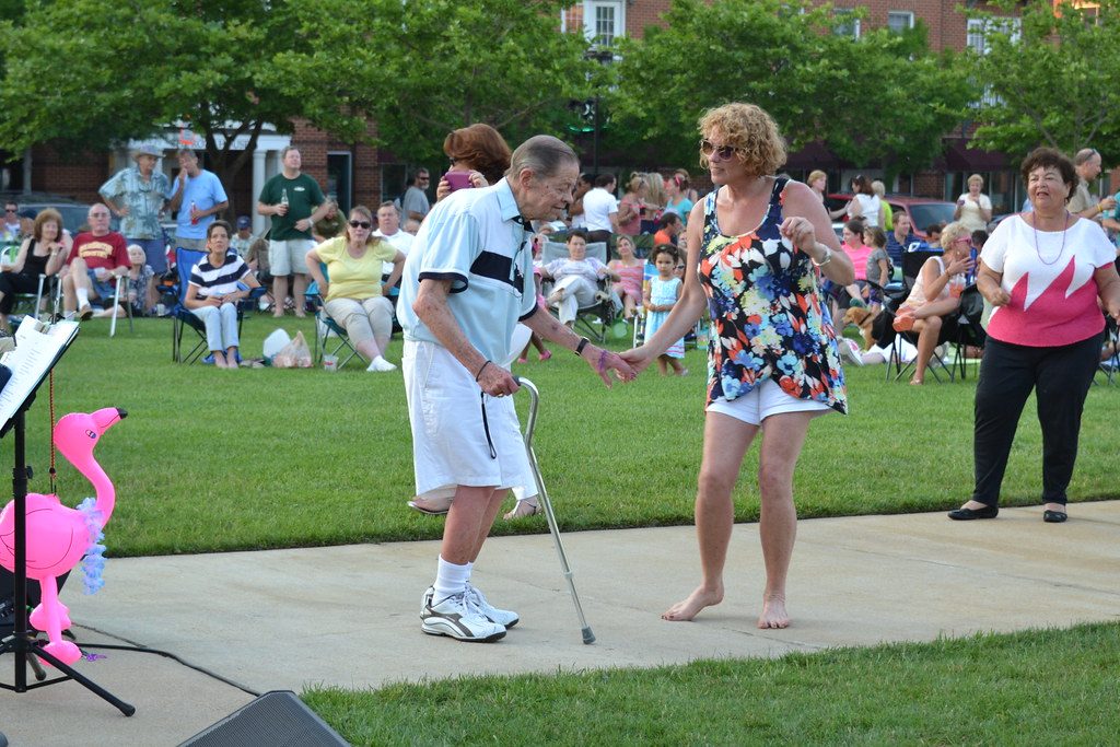 Stock photo of a senior enjoying gentle dance/movement at a community gathering. Model is not a client.