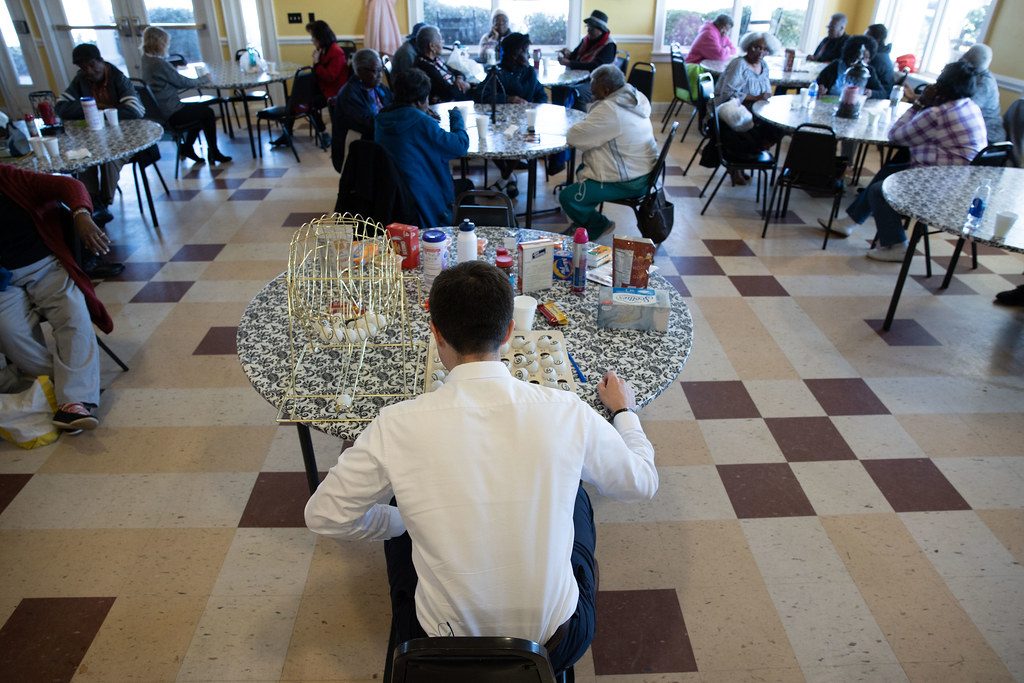 Stock photo of seniors in a day-program activity room during a group game. Models are not clients of this center.